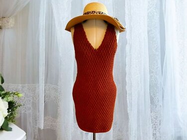 Rückenansicht rostbraunes gehäkeltes Kleid mit V-Ausschnitt auf Schaufensterpuppe mit Sonnenhut
