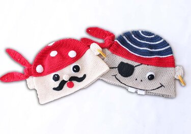 Zwei kreative gehäkelte Piratenmützen: eine mit rotem gepunktetem Bandana und Schnurrbart, die andere mit blau-weiß gestreifter Kappe und Augenklappe.