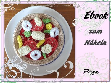 Gehäkelte Spielzeugpizza mit bunten Belägen auf weißem Teller; rechts rosa Feld mit Schrift ‚Ebook zum Häkeln‘.