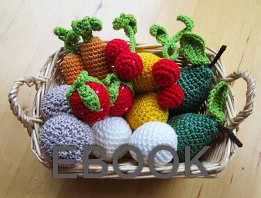Weidenkorb gefüllt mit gehäkeltem Obst und Gemüse wie Möhren, Kirschen, Erdbeeren und Birnen.