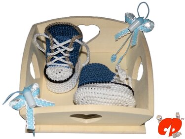 Gehäkelte Babyschuhe im blauen und weißen Sneaker-Stil in einem hellen Holztablett mit Herz-Ausschnitten und blauen Deko-Fläschchen.