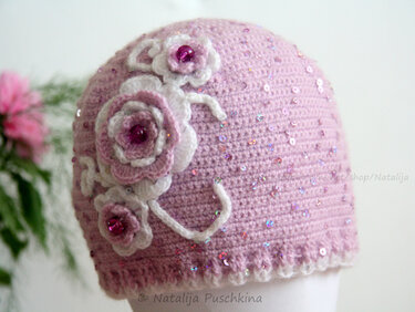 Rosafarbene gehäkelte Mütze mit weißen und rosa Blumenapplikationen und Pailletten
