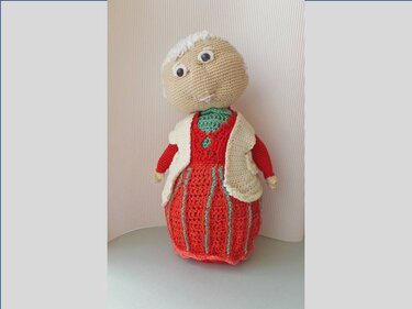 Gehäkelte Amigurumi-Oma mit rotem Kleid und cremefarbener Weste