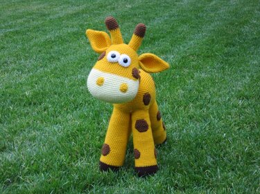 Gehäkelte gelbe Giraffe Amigurumi mit braunen Flecken auf Gras