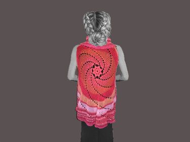 Rückansicht einer Person mit geflochtenen Haaren, die eine bunte, gehäkelte Weste mit großem Spiralmuster und Rüschen am Saum trägt.