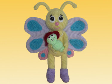 Gehäkeltes gelbes Schmetterlings-Amigurumi mit lila und türkisen Flügeln, hält eine mintgrüne Raupe