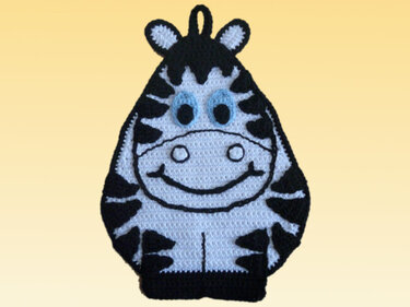 Gehäkelter Topflappen in Zebra-Form, schwarz-weiß mit blauen Augen auf hellem Hintergrund.