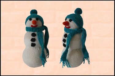 Zwei gehäkelte Schneemänner, weiß, mit türkiser Mütze und Schal, orangefarbener Nase und schwarzen Knöpfen
