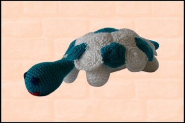 Gehäkelte Amigurumi‑Schildkröte in Türkis und Weiß mit kontrastierendem Panzer