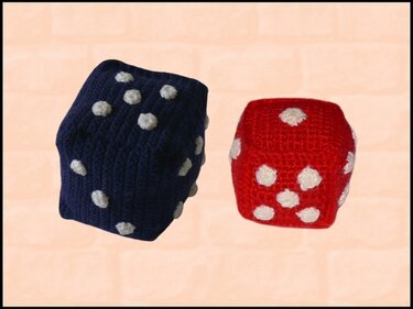 Zwei gehäkelte Spielwürfel, einer blau und einer rot, beide mit weißen Punkten