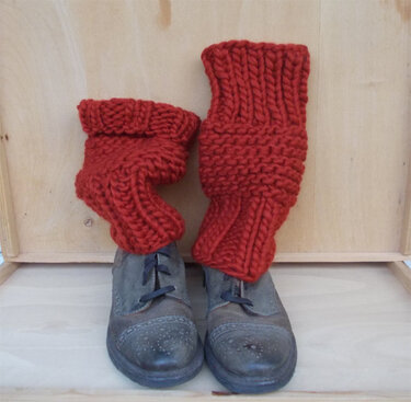 Rote grob gestrickte Beinstulpen über dunklen Leder-Ankle-Boots