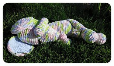 Gehäkelte Amigurumi‑Maus mit Pastellstreifen auf grünem Gras