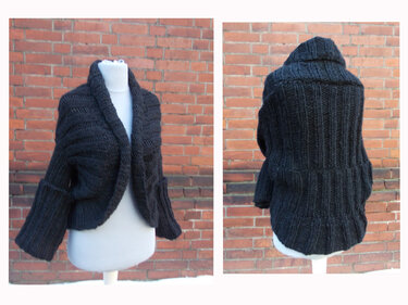 Kurze schwarze Strickjacke aus Grobstrick mit Rippenmuster und breitem Schalkragen auf Schneiderpuppe, Vorder- und Rückansicht