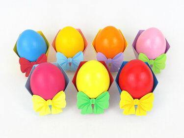 Gefaltete Papierhalter mit bunten Eiern und dekorativen Schleifen