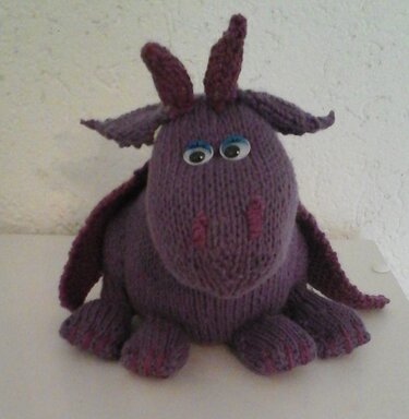 Handgestrickter lila Amigurumi‑Drache mit Hörnern, Flügeln und Kulleraugen