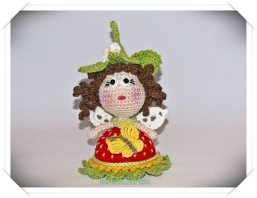Gehäkelte Amigurumi-Puppe mit grünem Blatt-Hut, weißen Flügeln und gelbem Schmetterling