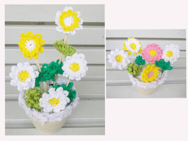 Topf mit gehäkelten Blumen auf Stäbchen und grünen Blättern