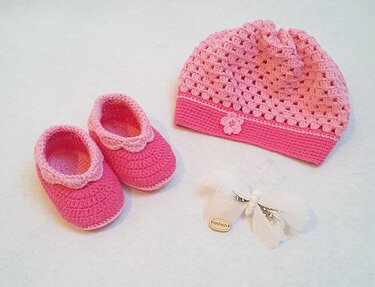 Rosa gehäkelte Babymütze mit Blütenapplikation und passende Babyschühchen