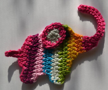 Gehäkelte Elefanten-Applikation in Regenbogenfarben auf hellem Hintergrund