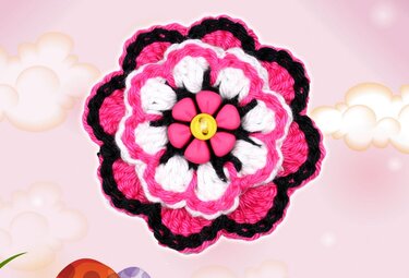 Mehrlagige gehäkelte Blume in Pink, Weiß und Schwarz mit blütenförmigem rosa Element und gelbem Knopf in der Mitte