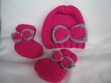 Gestrickte pinke Babymütze und passendes Paar Schühchen mit grauen Schleifen