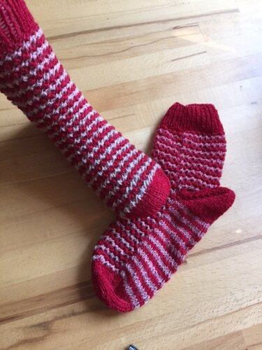 Gestrickte rot-weiße Damensocken mit Rippenbündchen und einfarbiger Ferse auf Holzuntergrund