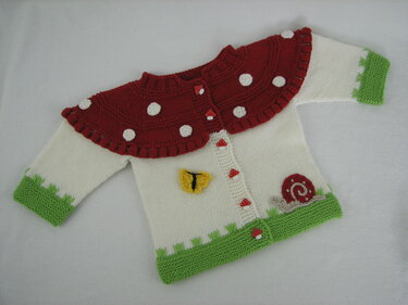 Gestrickte Babyjacke weiß mit rotem Pilzkragen, grünen Bündchen und Pilzknöpfen
