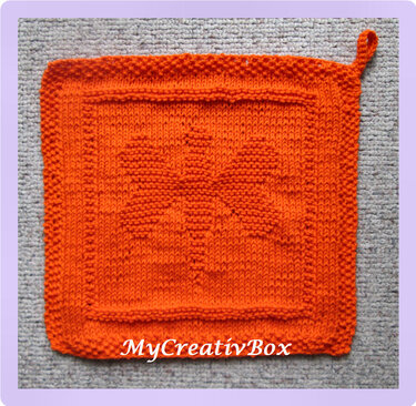 Leuchtend oranger gestrickter Topflappen mit Schmetterlingsmotiv und Aufhängeschlaufe