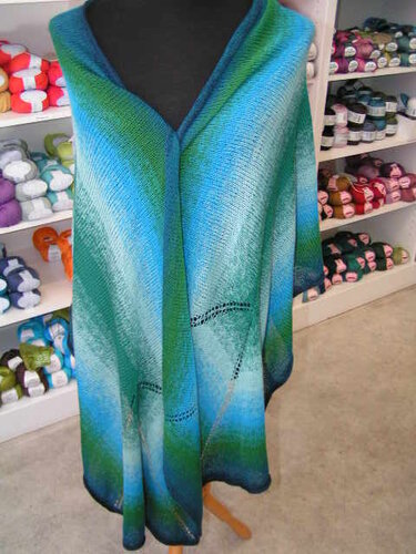 Gestricktes Dreieckstuch in Blau‑Grün‑Verlauf mit Lochmuster auf Schneiderpuppe.