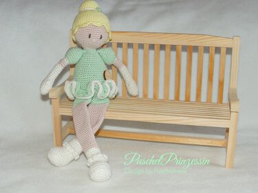 Gehäkelte Amigurumi-Ballerina in Hellgrün und Rosa auf Mini-Holzbank