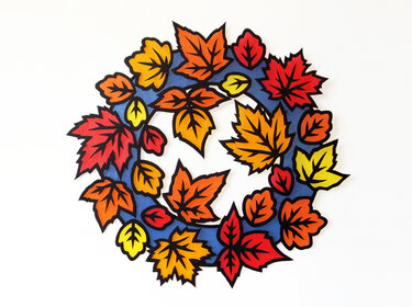 Kreisförmiger Herbstkranz aus roten, orangefarbenen und gelben Papierblättern vor blauem Hintergrund