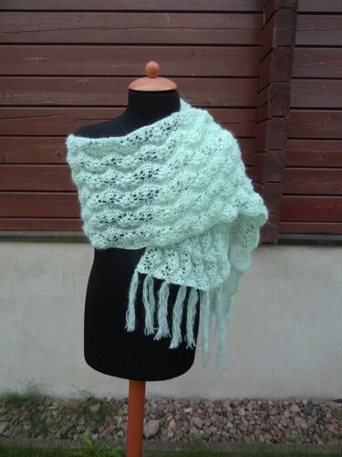 Hellgrüner gestrickter Schal mit Ajourmuster und langen Fransen auf einer schwarzen Schaufensterpuppe