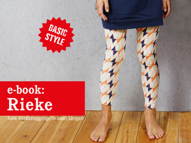 Unterkörper eines Kindes in gemusterten Leggings und dunkelblauer Tunika, barfuß auf Holzfußboden
