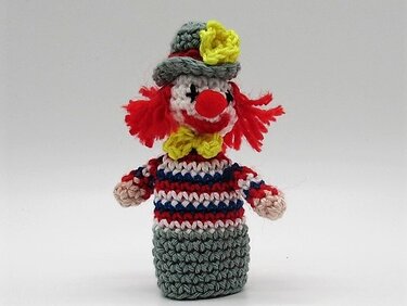 Gehäkelte Clown-Fingerpuppe mit gestreiftem Körper, roter Nase und rotem Garnhaar