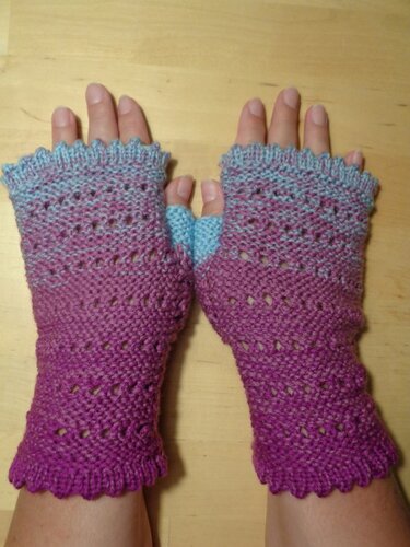 Fingerlose gestrickte Armstulpen mit lila-blauem Farbverlauf und Lochmuster, an Händen getragen.