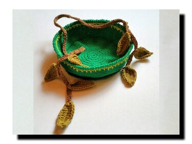 Runder grüner gehäkelter Korb mit brauner Blattranke, olivgrünen Blättern und gelbem Rand