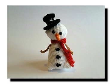 Gehäkelter weißer Schneemann mit schwarzem Zylinder und rotem Schal