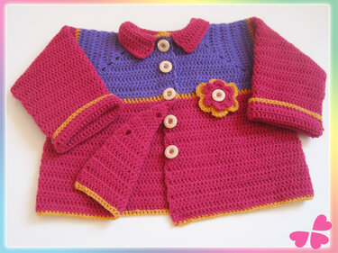 Gehäkelte Babyjacke pink und lila mit gelber Zierkante, Knopfleiste und Blumen-Applikation, liegend