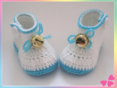 Gehäkelte weiße Babyschuhe mit türkisfarbener Kante und goldenen Glöckchen