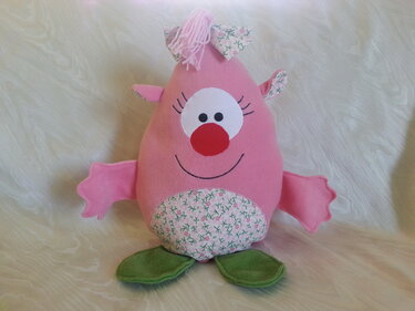 Rosa genähtes Kuscheltier mit Blumenapplikation, roter Nase und grünen Füßen