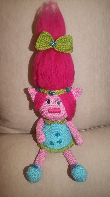 Amigurumi-Puppe mit pinker Haarpracht, grüner Schleife und türkisfarbenem Kleid