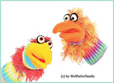 Zwei farbenfrohe gehäkelte Handpuppen mit großen Augen und Schnäbeln
