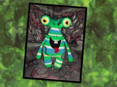 Gehäkeltes gestreiftes Amigurumi-Monster mit gelben Augen und roter Zunge