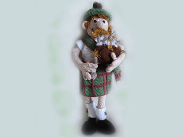 Crocheted amigurumi doll in green kilt holding bagpipes