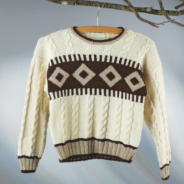 Cremefarbener Kinderpullover mit braunen Rauten und Zopfmustern