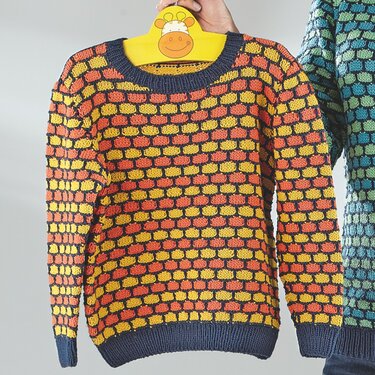 Gestrickter Kinderpullover in Orange und Gelb mit dunkelblauen Bündchen an einem gelben Giraffenbügel
