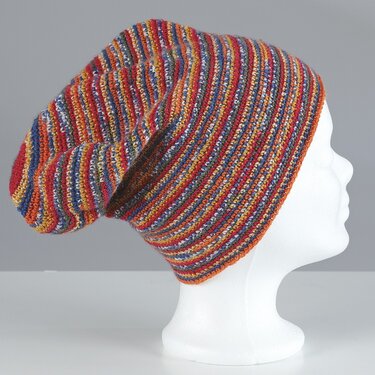 Bunte, gestreifte gehäkelte Oversize-Beanie auf einem weißen Schaufensterkopf, seitliche Ansicht.