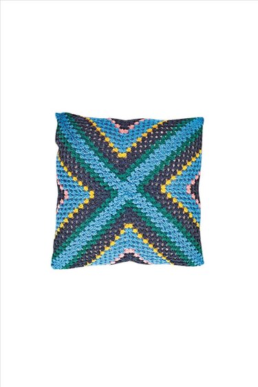 Quadratisches handgehäkeltes Kissen mit diagonalem X‑Muster in Blau, Gelb und Rosa