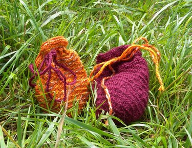 Zwei gestrickte Geschenkbeutel in orange-meliert und bordeaux im Gras