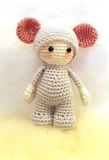 helle gehäkelte Amigurumi-Puppe mit rosa Ohren und schwarzen Augen
